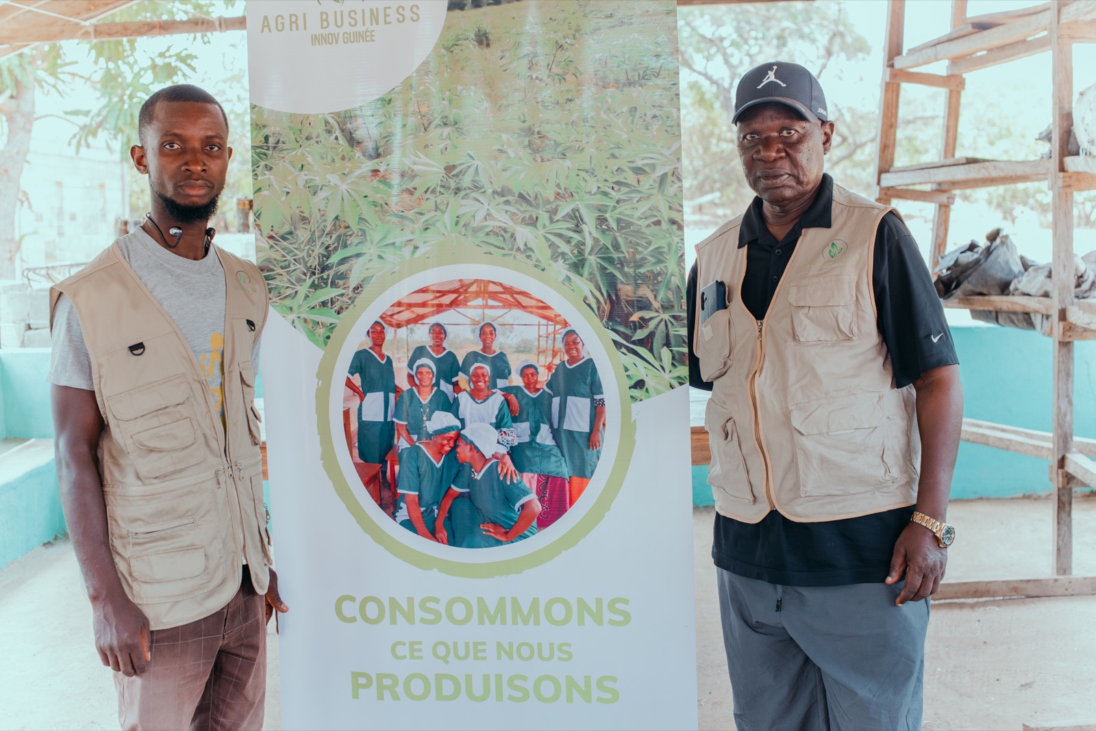 Deux membres de l'équipe ABIG devant le kakémono « Consommons ce que nous produisons ».